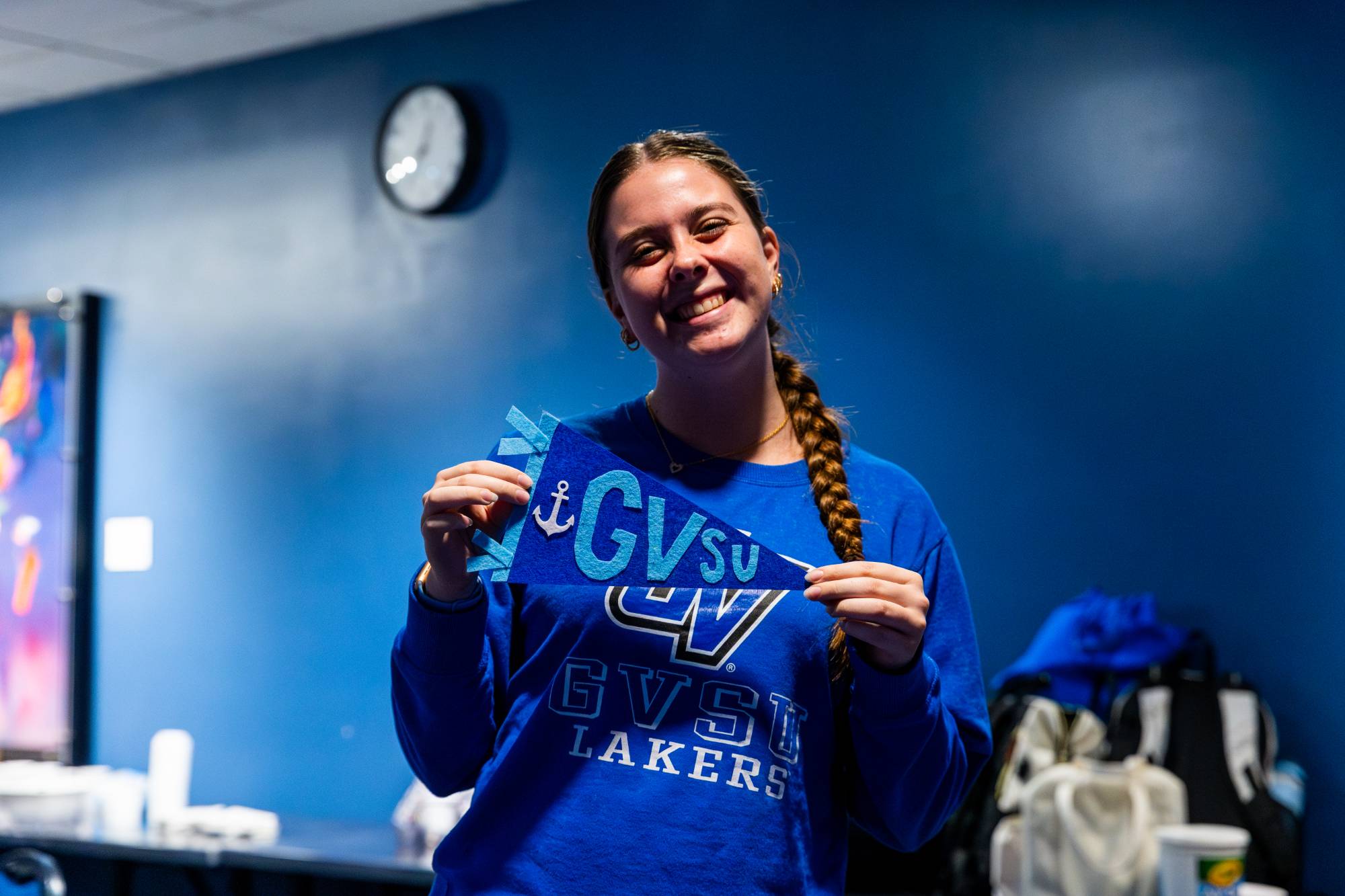 female student holding blue pennant that reads grand valley